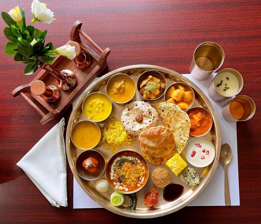Traditional Rajasthani vegetarian thali served in brass plates with dal baati churma, gatte and bajra roti